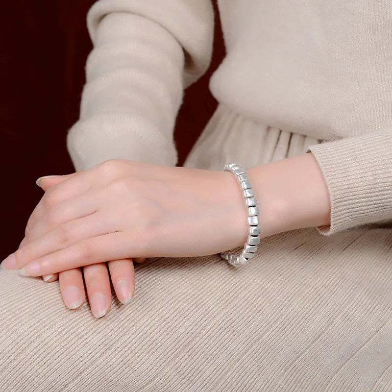 Handmade women's bracelet with an irregular silver square pendant on a wooden elastic band.