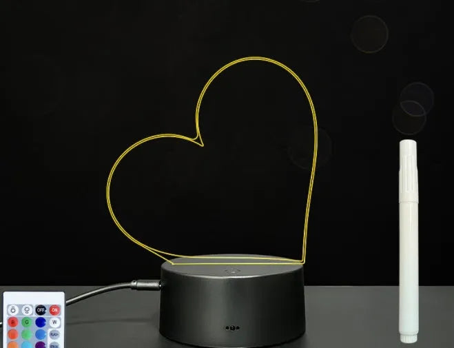 Black 3D acrylic message board night light with remote control and stylus on desk.
