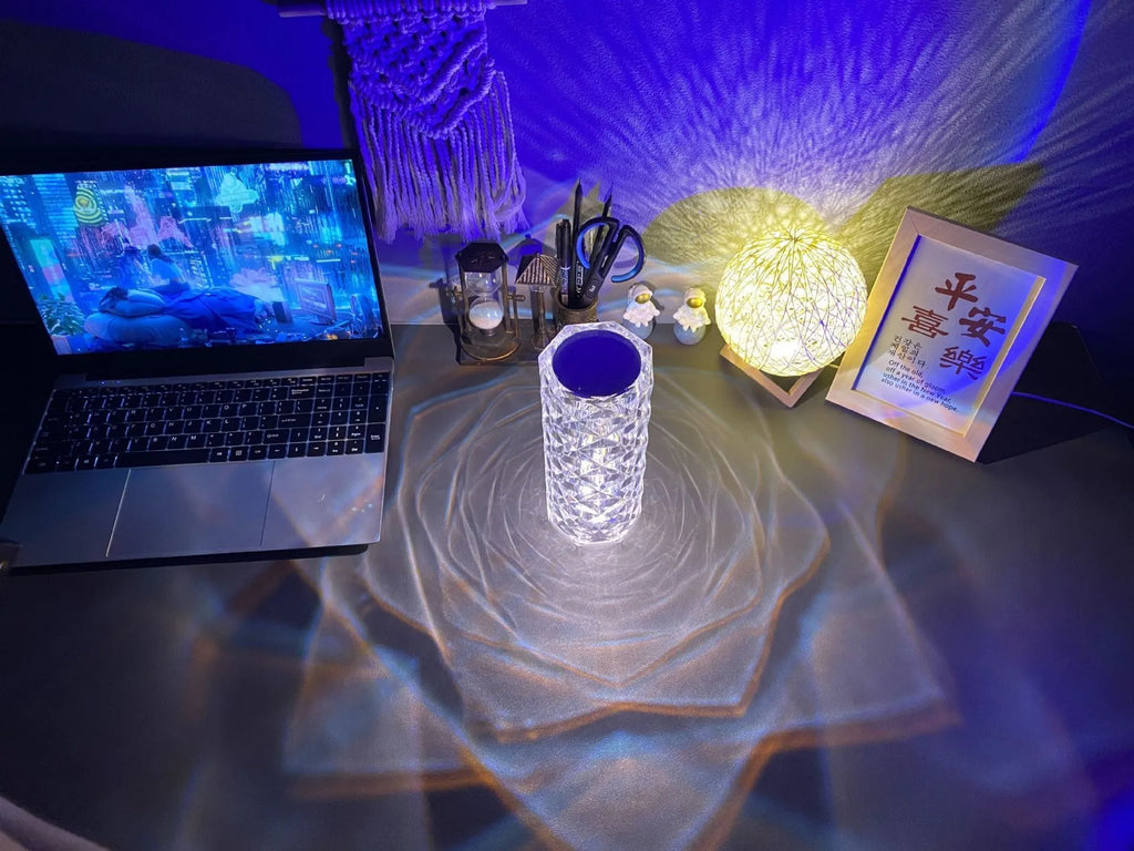 Clear acrylic crystal rose shaped LED table lamp with diamond-like facets on a table.