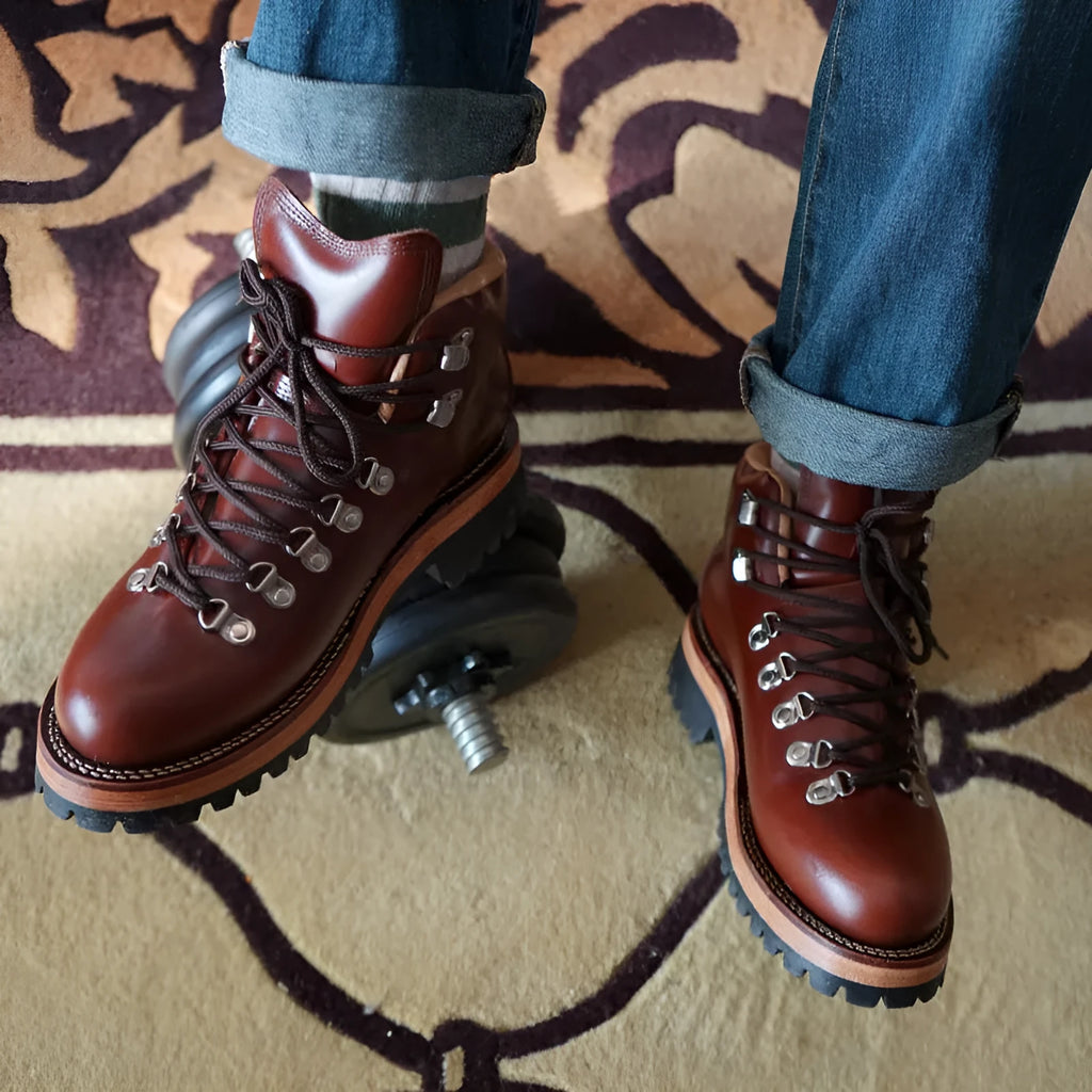 Men's brown leather city hiking boots with lace-up closure on a wooden surface