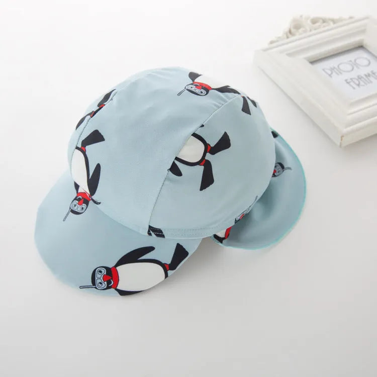 Boy in penguin print long sleeve one-piece swimsuit and matching swimming cap