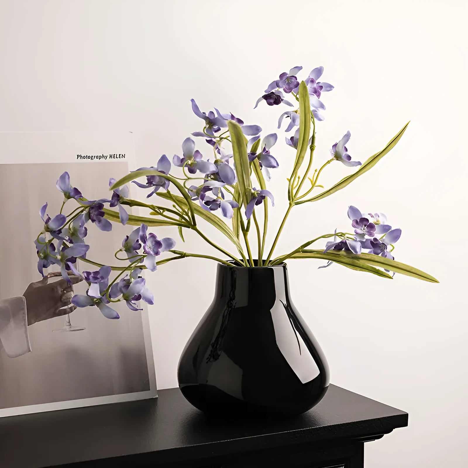 Modern ceramic vase with two white artificial orchid stems in minimalist home setting