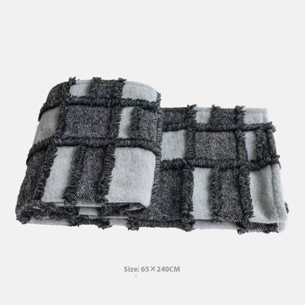 Modern grey and white plaid bed runner set with matching pillowcase and a brown leather round pillow on a bed.