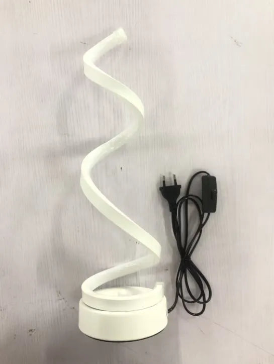 Modern LED table lamp with gold metal base and curved acrylic shade on a desk