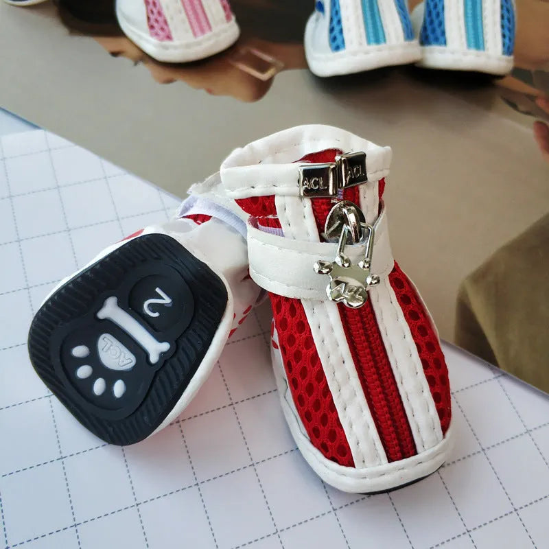 Four pairs of blue, pink, and red cloth dog shoes with zip fastenings on a white background.