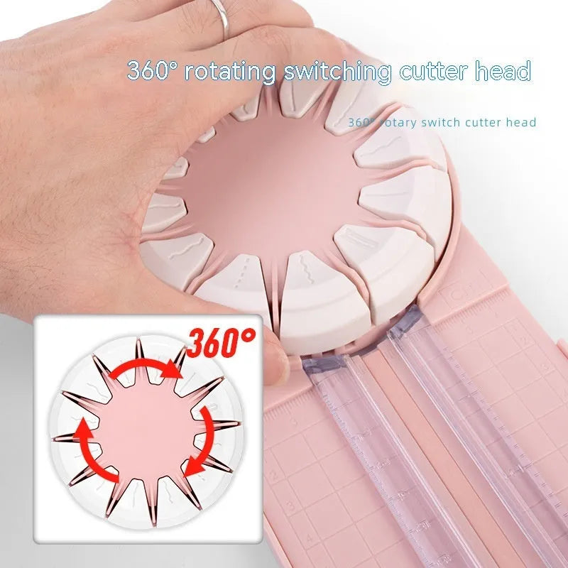 Pink and black 12-in-1 dotted line plastic rotary paper cutting machine on a craft table.