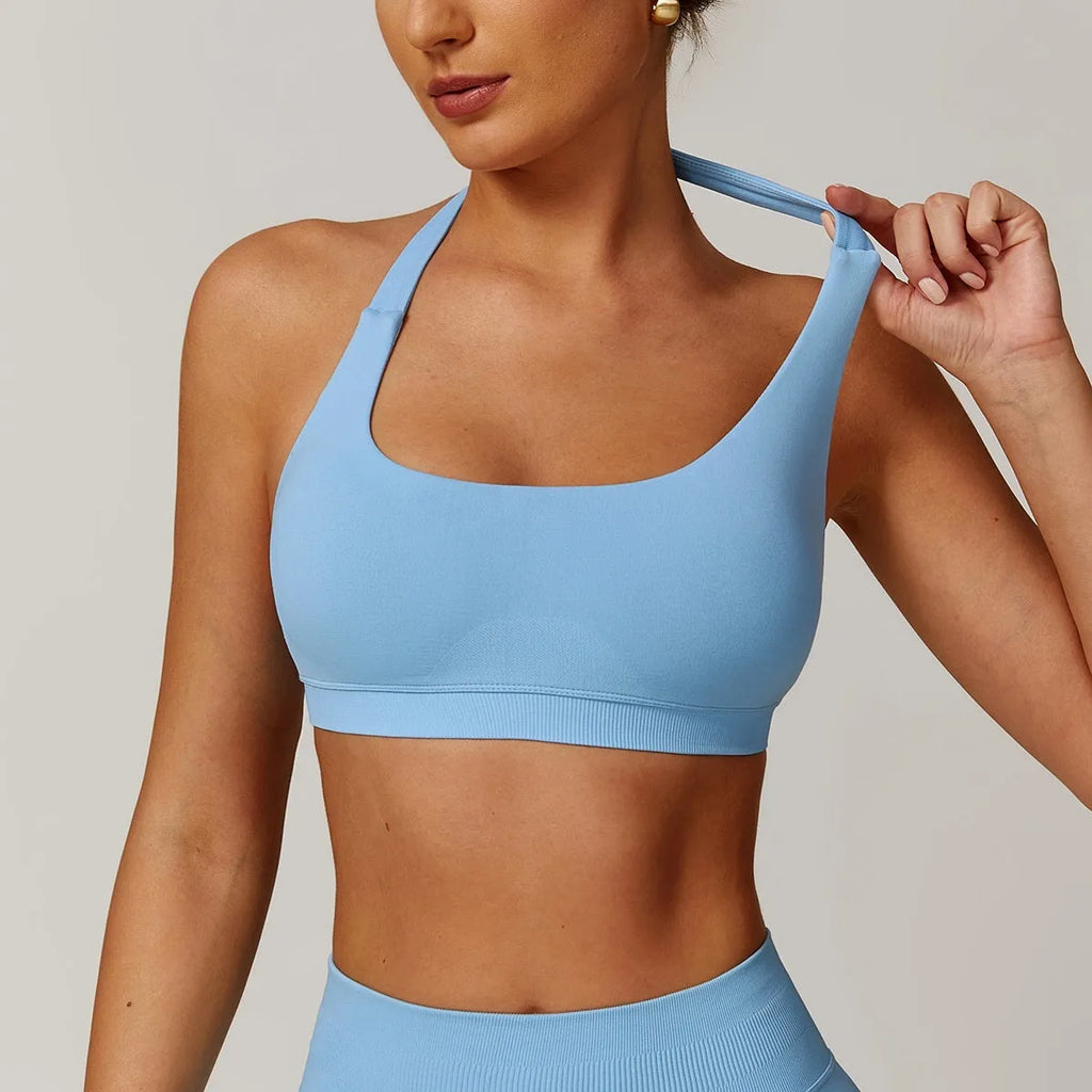 Women's black halter neck sports bra with removable padding on a grey background, showing back and front detail.