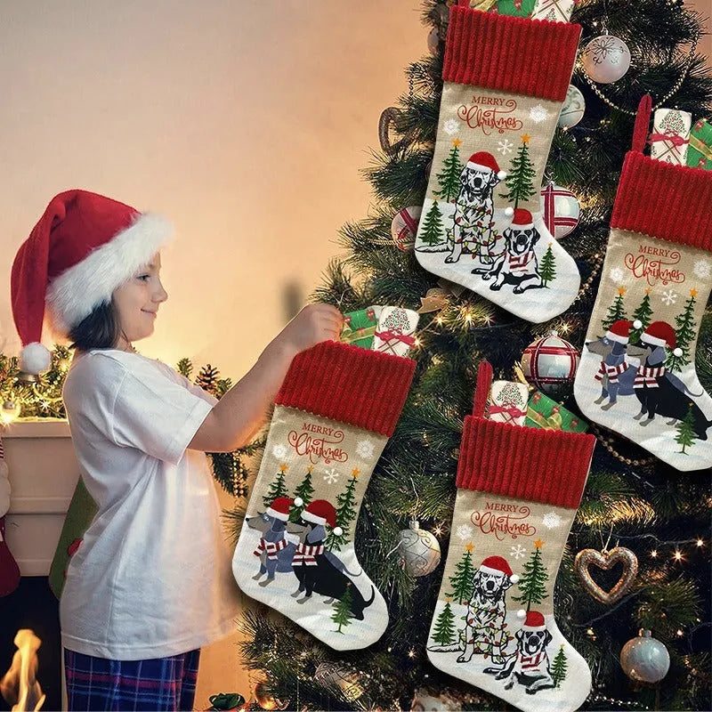 Red and green cloth Christmas stocking pendant for pets, hanging on a tree branch.