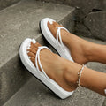 A pair of thick-soled herringbone pattern flip-flop slippers on a solid background.
