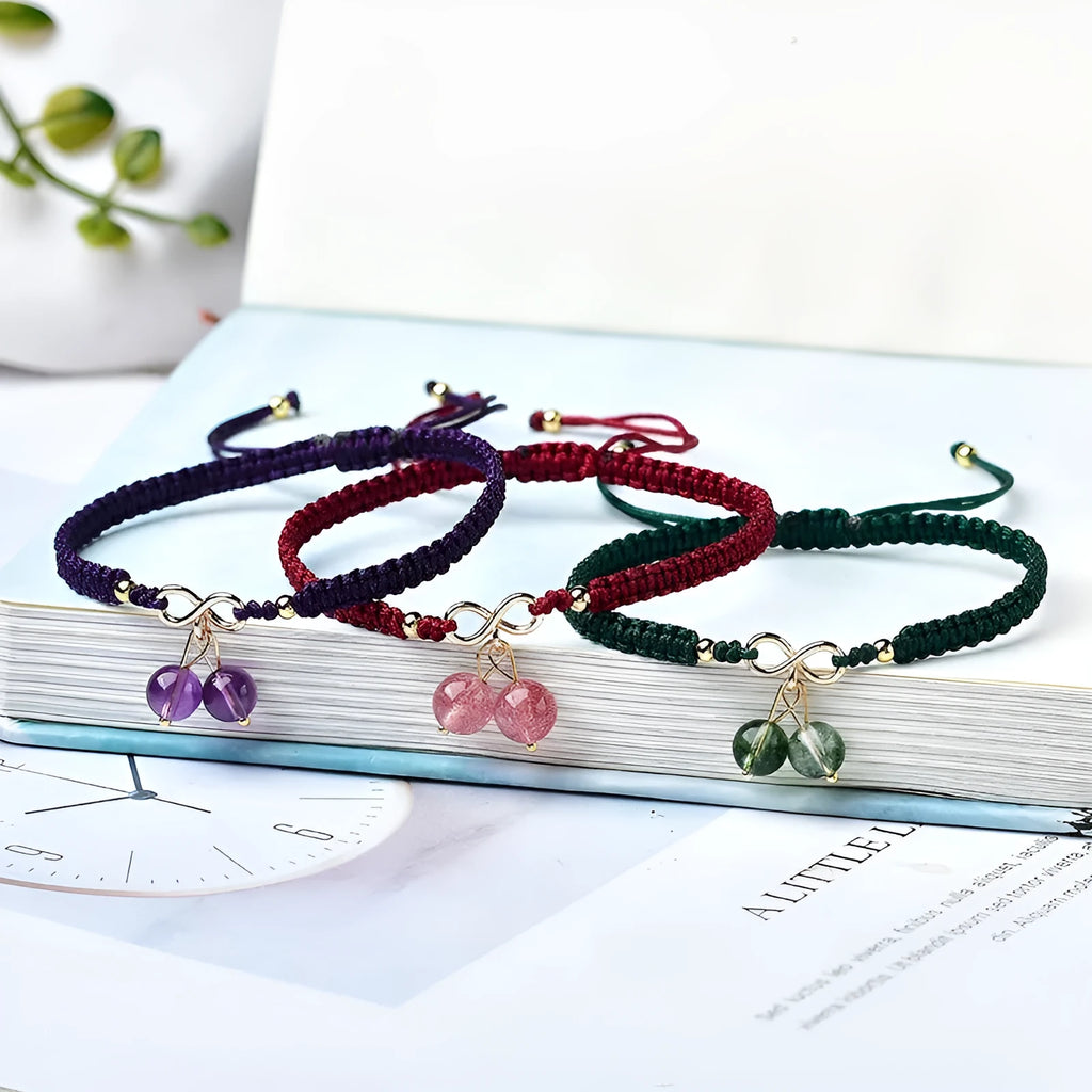 Close-up of a women's strawberry quartz bracelet with red cherry-shaped beads on a stretch cord.