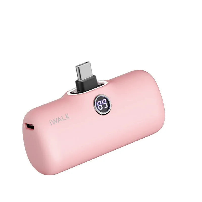 Compact white lipstick-shaped power bank with digital battery percentage display on a wooden table.