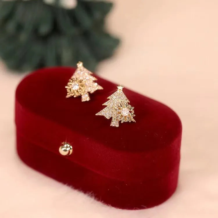 Pair of rotatable Christmas tree stud earrings with rhinestone snowflake detail in gold on a white background