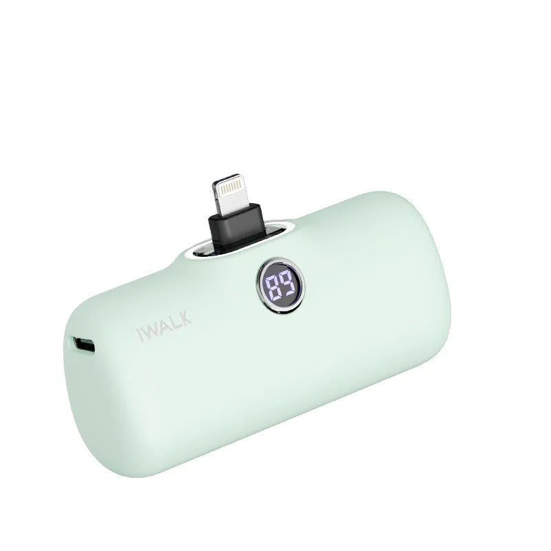 Compact white lipstick-shaped power bank with digital battery percentage display on a wooden table.