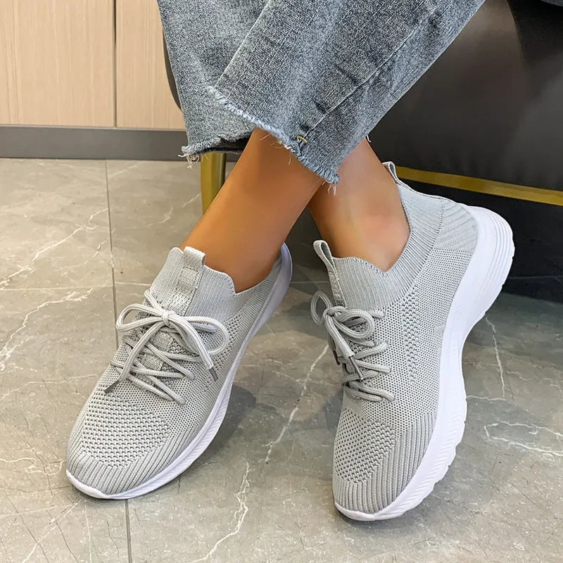 Women's low-top mesh running shoes in creamy white with a Flyknit upper and flat rubber sole.