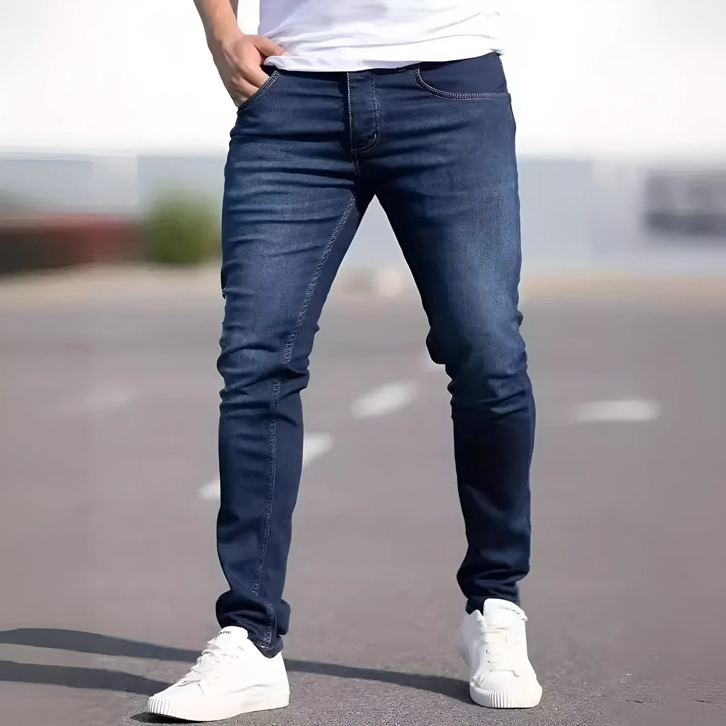 Dark blue men's slim-fit cotton jeans with a skinny leg opening on a plain background.