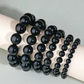 Hand-woven round obsidian bead bracelet on a wrist, showing ethnic style and multiple colour options.