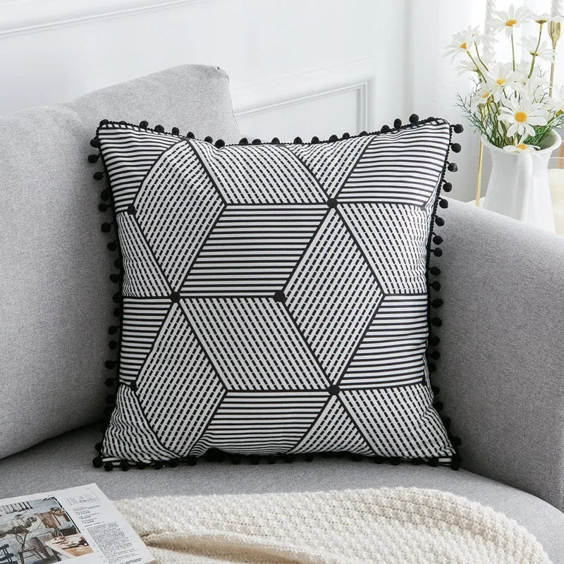 Bohemian style decorative throw pillow with polyester cover in light grey on a sofa.