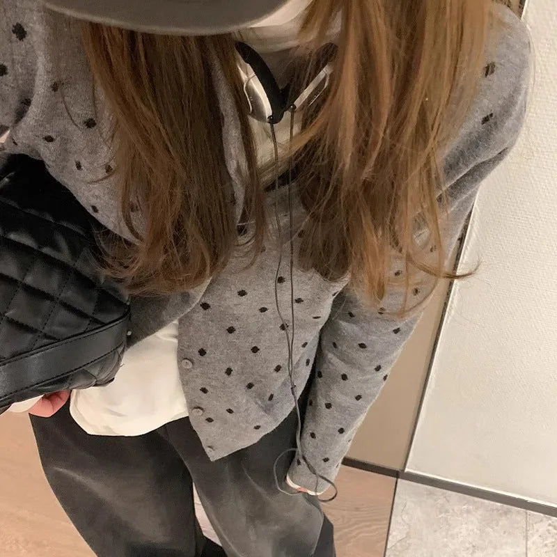 Women's loose grey dot patterned knitted cardigan with crocheted flower details on the front.