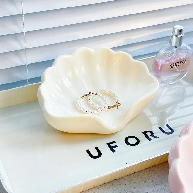 White or pink plastic shell-shaped soap dish for bathroom sink or shower.