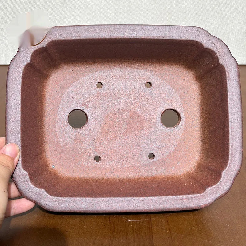 Reddish brown hand-glazed stoneware rectangular bonsai flower pot on a flat surface