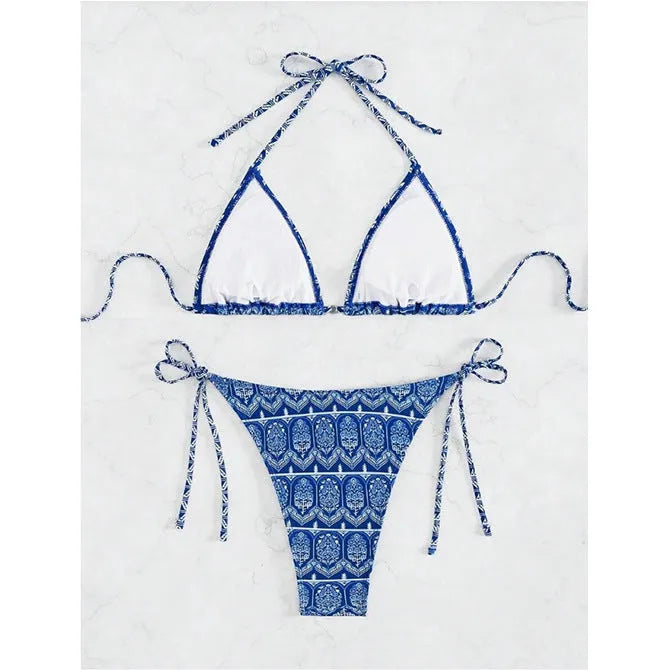 Women's green split bikini swimsuit with bandage-style stitching on a beach.