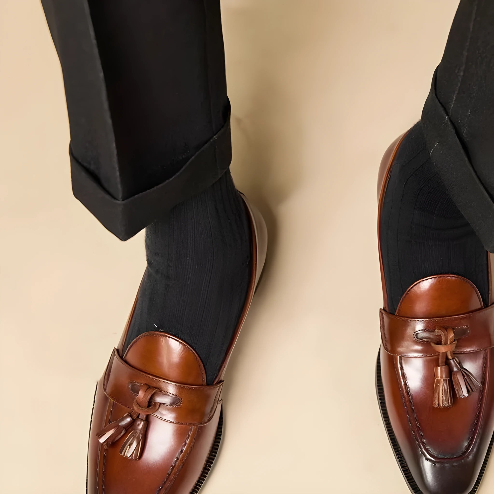 Men's black and brown polished leather tassel loafers for business casual wear, shown from the side.