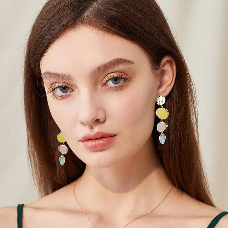 A pair of simple disc-shaped alloy earrings with a Morandi three-colour oil-drip wash finish.