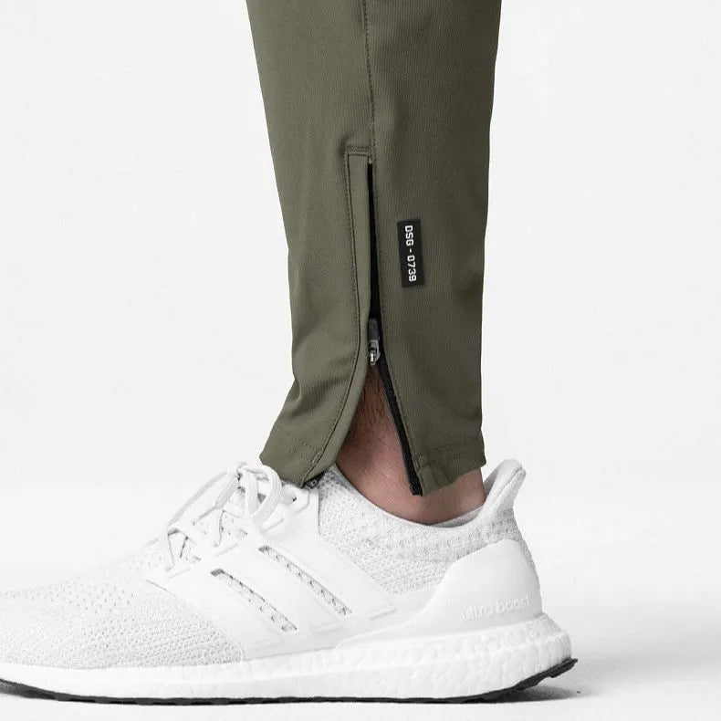 Man wearing dark grey loose-fit ankle-tied fitness trousers made from quick-drying polyester.