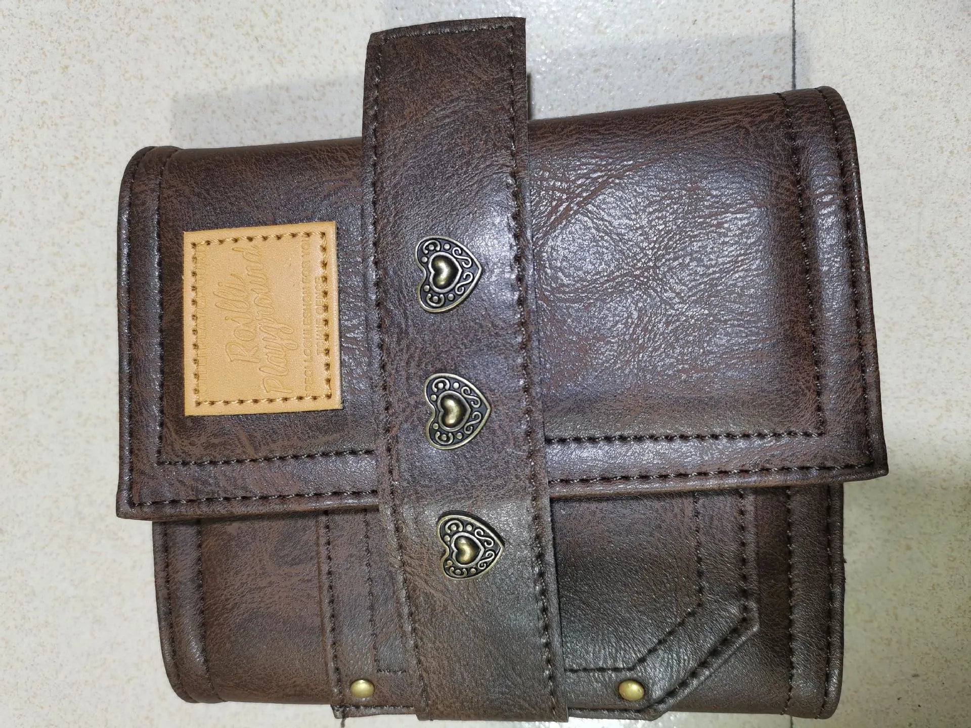 Brown retro-style A7 notebook with a PU leather-look cover and metal buckle closure, showing loose-leaf binding.