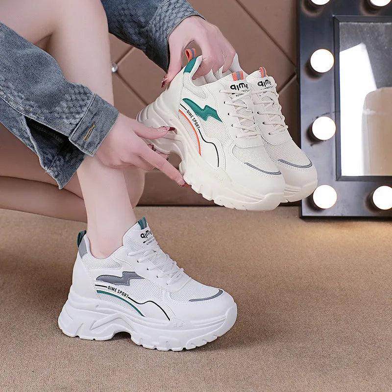 Women's white low-top sports trainers with cross shoulder straps and a lace-up front on a solid background.