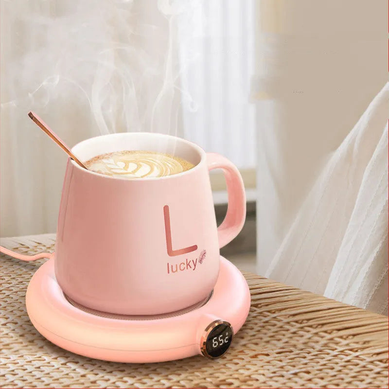 White USB cup warmer pad with LED display on a desk next to a coffee mug.