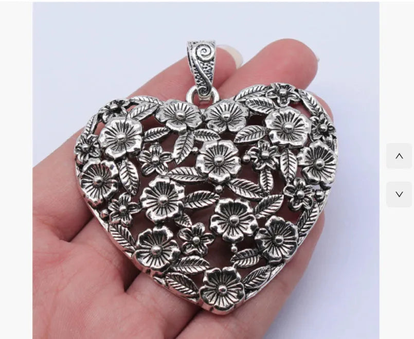 Ancient silver hollow flower love symbol alloy pendant on a dark background.