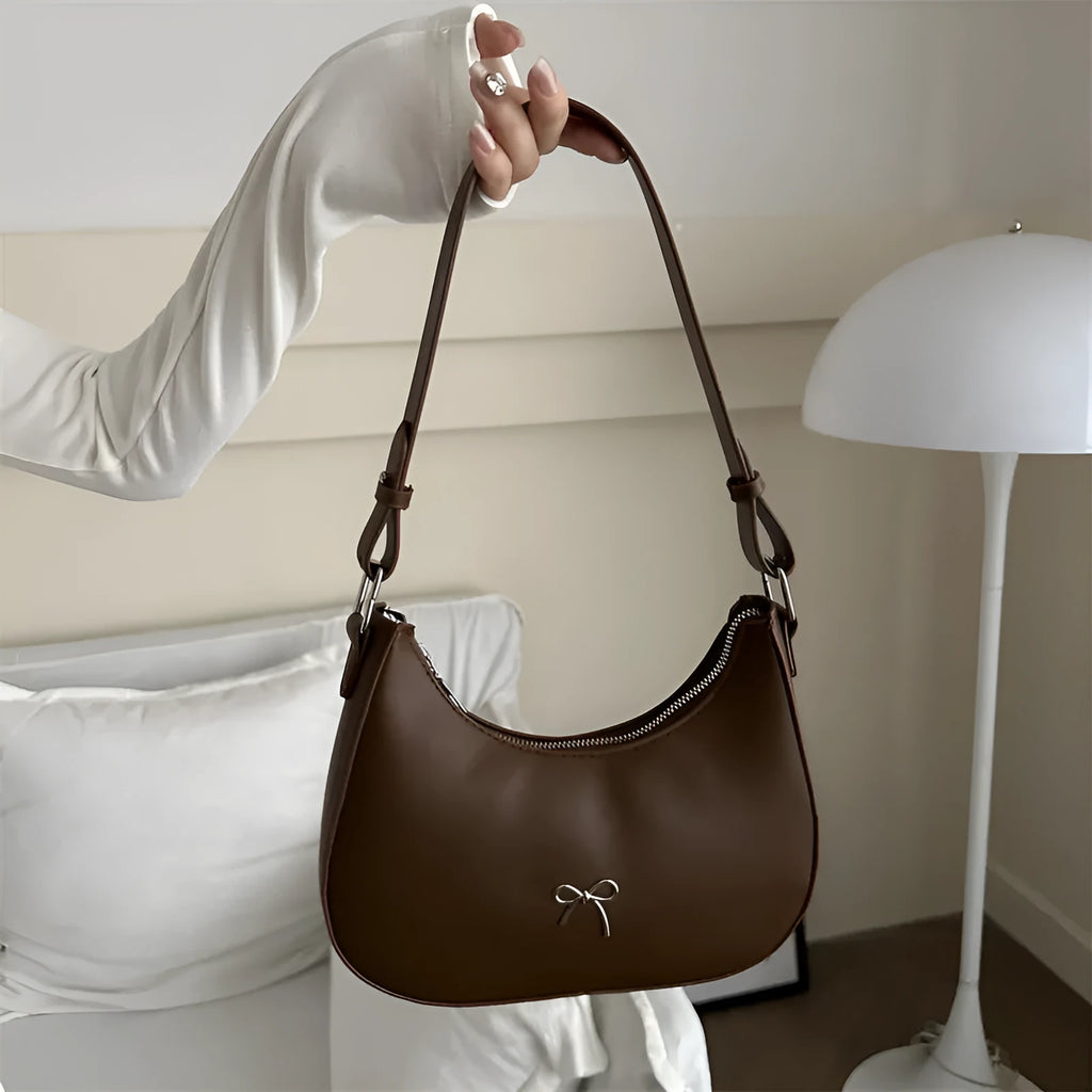 Women's black dumpling-shaped PU shoulder baguette handbag with a single strap and sewing thread detail.