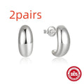 Close-up of a glossy C-shaped sterling silver stud earring on a gold background.