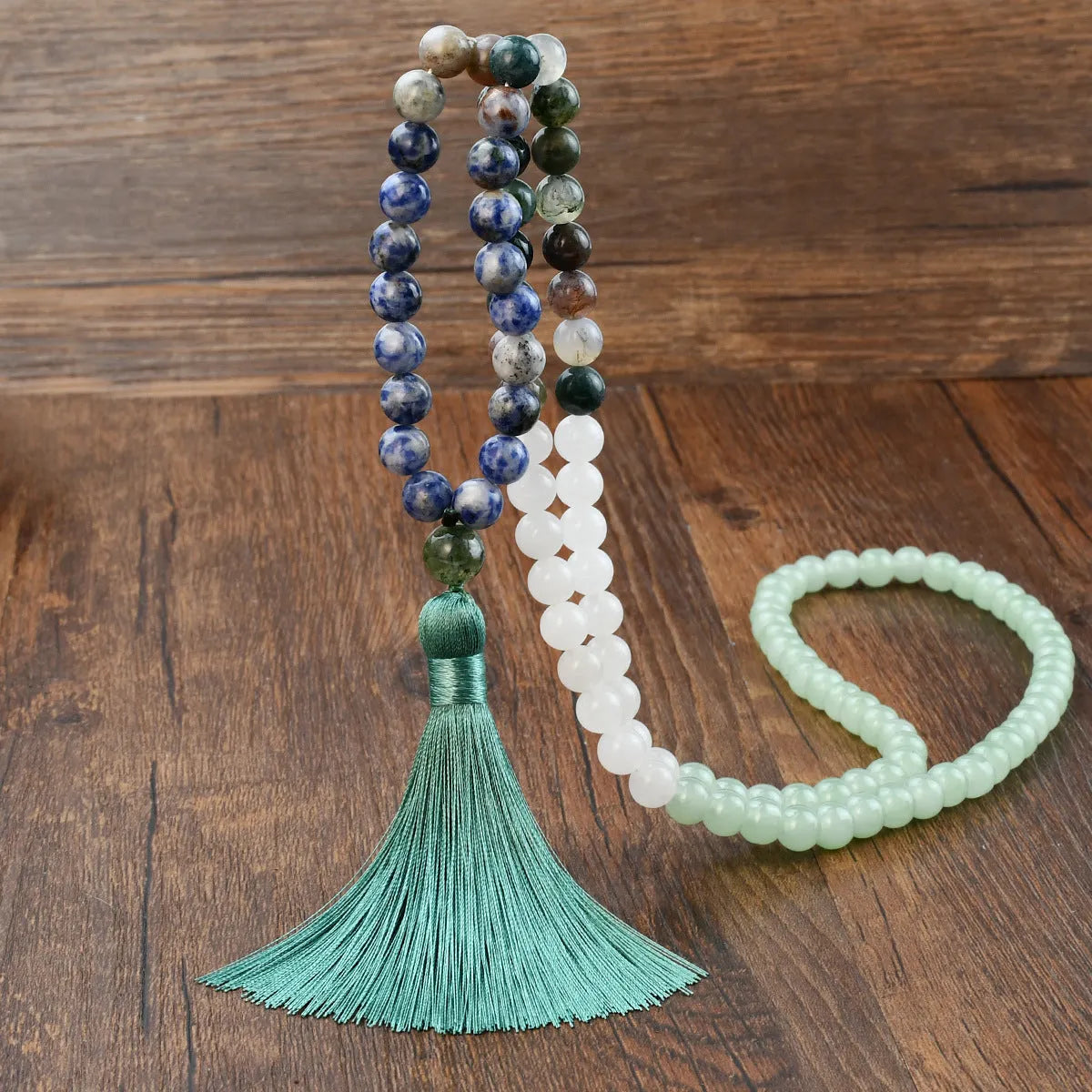A long bohemian-style necklace with a geometric mixed gemstone pendant and a coloured tassel on a ball bead chain.