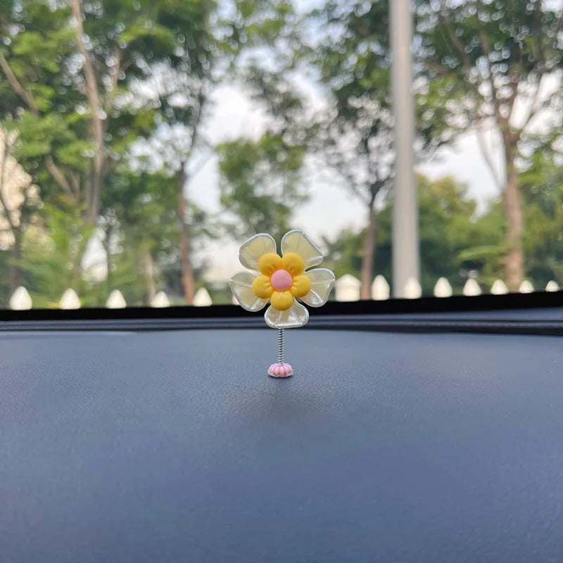 Small colourful plastic swing car decoration on a car dashboard, showing blue, green, pink, purple, and yellow colour options.