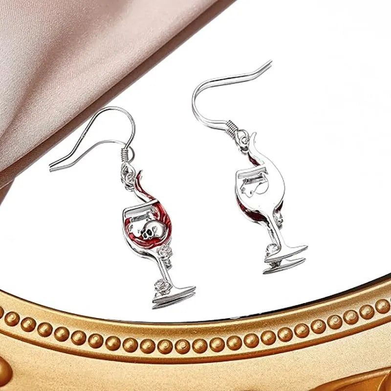 A pair of silver-toned drop earrings featuring a detailed geometry skull design combined with a wine glass shape.