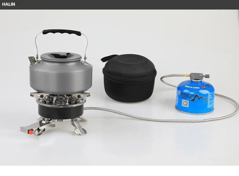 Silver portable folding camping stove with extended copper gas hose, shown on a wooden picnic table.