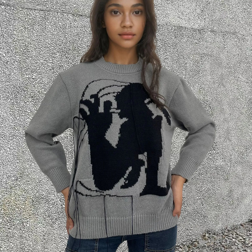 Grey women's alpaca wool sweater with abstract pattern and tassel detailing on a hanger.