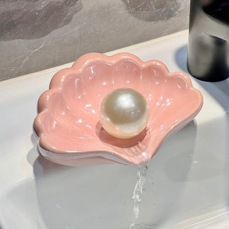 White or pink plastic shell-shaped soap dish for bathroom sink or shower.