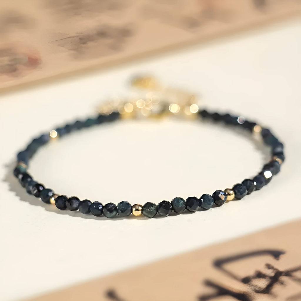 Blue tourmaline gemstone bracelet with 3mm cut beads on a white background.