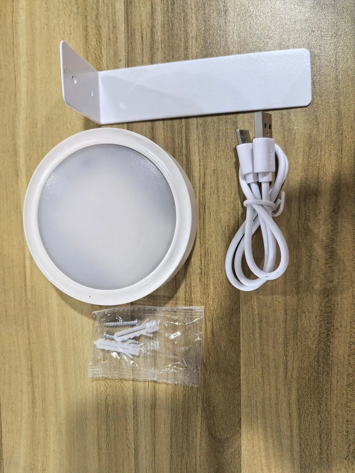 Black magnetic wireless LED lamp with remote control mounted next to a painting on a wall.