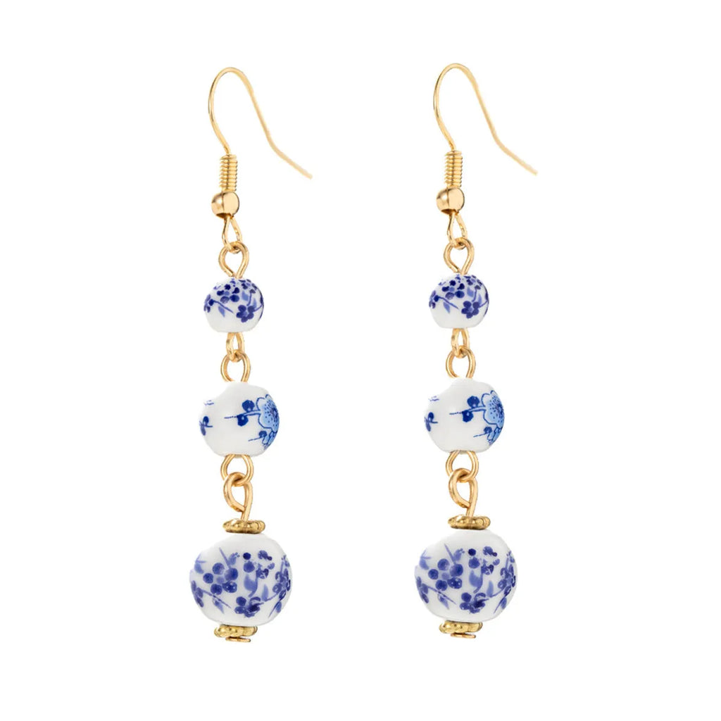 Long blue and white porcelain ceramic bead earrings with geometric alloy details on a white background.