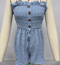 A woman wearing a solid blue off-shoulder sleeveless jumpsuit with a button detail at the front.