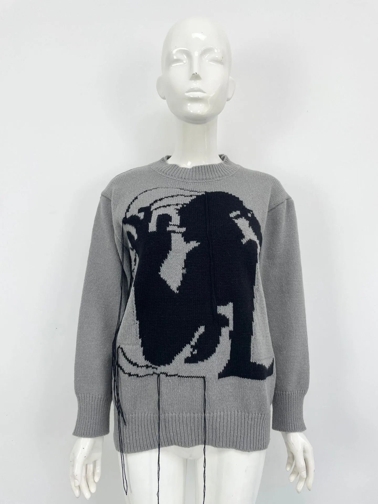Grey women's alpaca wool sweater with abstract pattern and tassel detailing on a hanger.