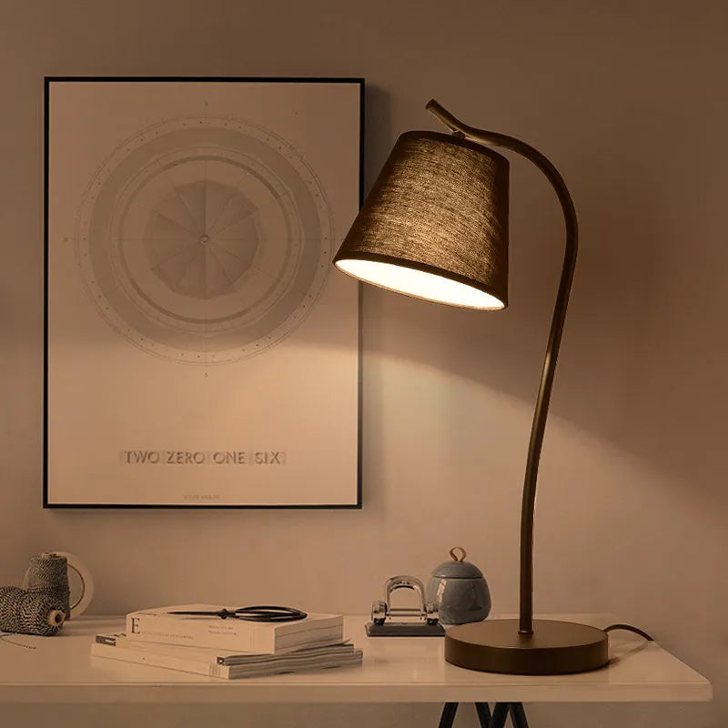 A simple modern Nordic style LED desk lamp with a dimmer switch on a desk.