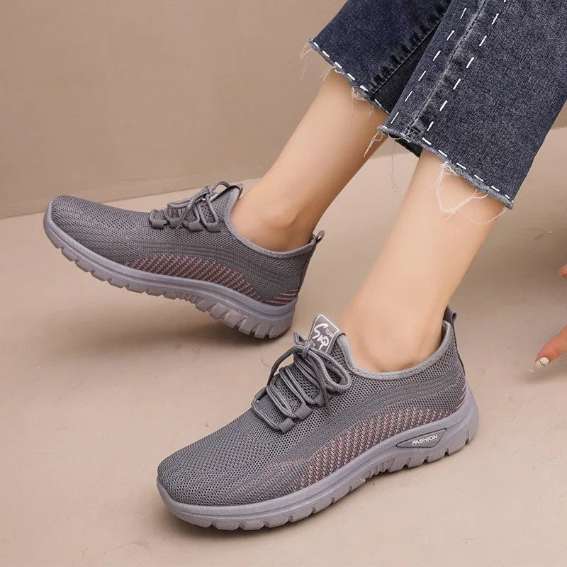 Women's black mesh sneakers with cross-strap detail and round toe on a rubber sole.