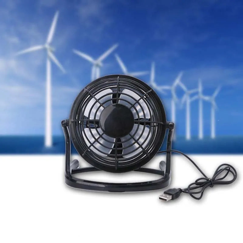 Small black and white USB desk fan with adjustable angle on a wooden table.
