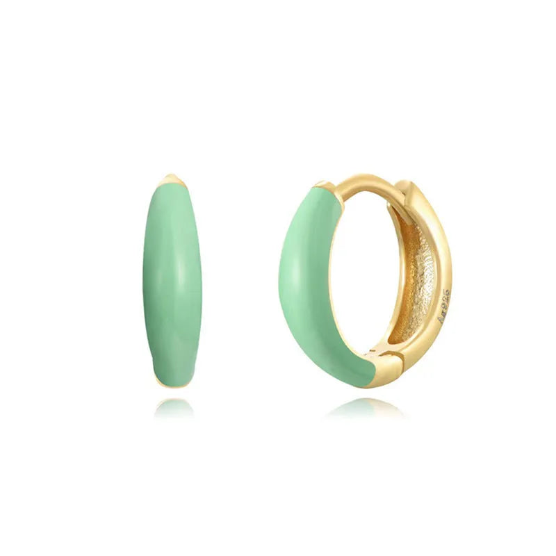 A pair of oval glossy light green epoxy dome earrings on a silver-toned U-shaped geometric wire, against a neutral background.