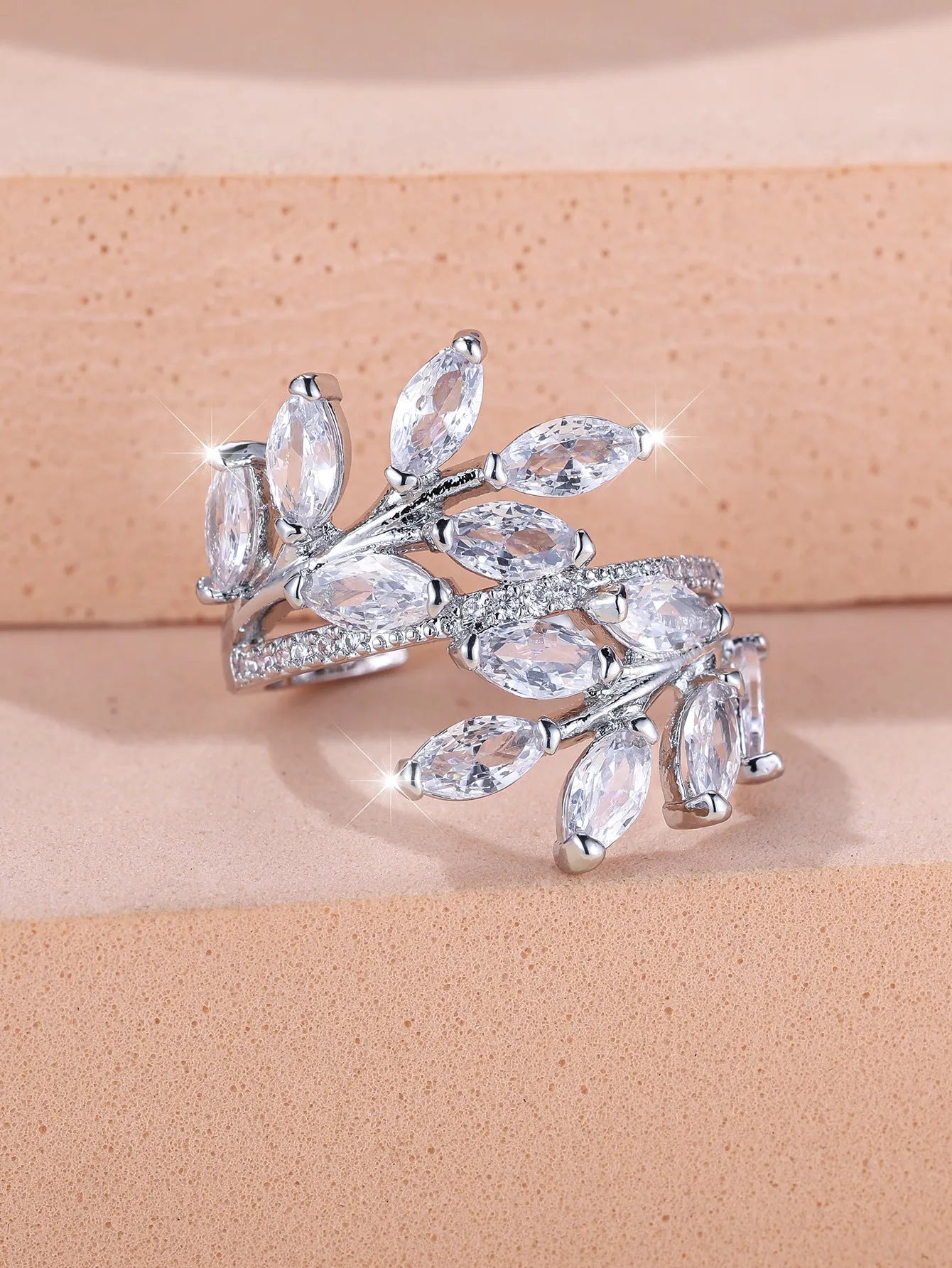 Adjustable copper leaf ring with a central zircon stone on a finger, showing rose gold and platinum colour options.